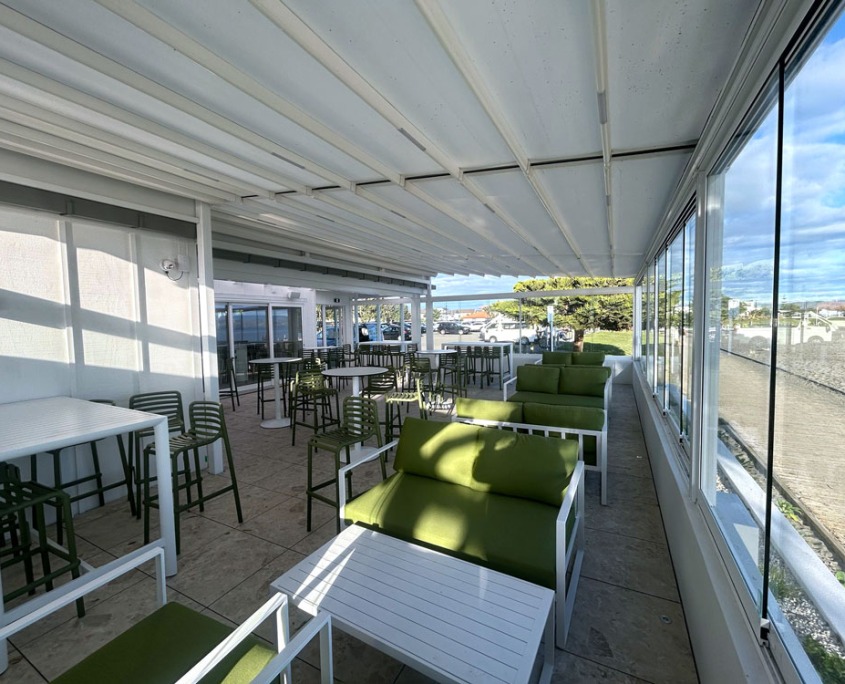 Cocktail bar outdoor area with retractable roof with beach and blue sky in the background