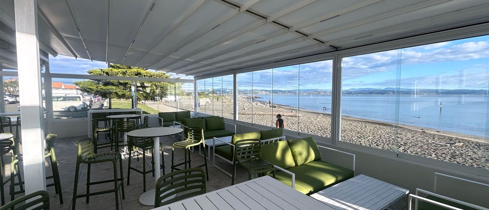 Cocktail bar outdoor area with retractable roof with ocean and blue sky in the background