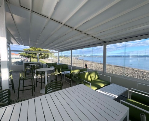 Cocktail bar outdoor area with retractable roof with ocean and blue sky in the background